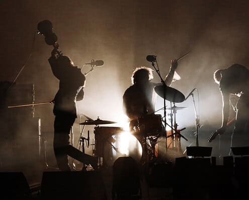 Dirty Three_SF 2016_credit Prudence Upton 059 Vita di scena di una band musicale dal vivo con luci soffuse e atmosfera intensa.