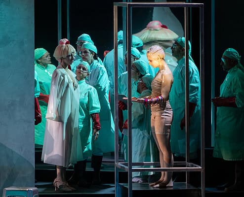 Vita di scena di due artisti musicali Scene teatrale con interpreti in costumi medici e figura femminile in gabbia di vetro.