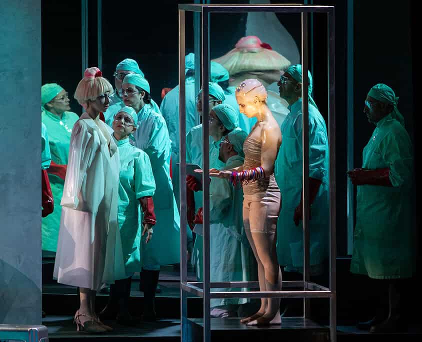 Vita di scena di due artisti musicali Scene teatrale con interpreti in costumi medici e figura femminile in gabbia di vetro.