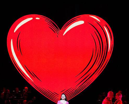 Cuore gigante sul palco Cuore rosso gigante sul palco con performer in abiti colorati.