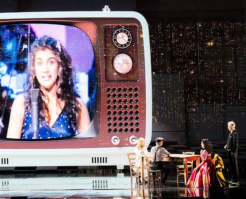 Spettacolo musicale con grande schermo vintage Performers on stage with a giant vintage TV screen displaying a singer, during a musical show at Le.