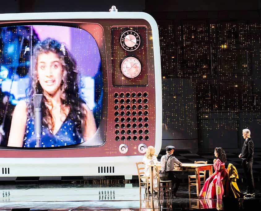 Spettacolo musicale con grande schermo vintage Performers on stage with a giant vintage TV screen displaying a singer, during a musical show at Le.