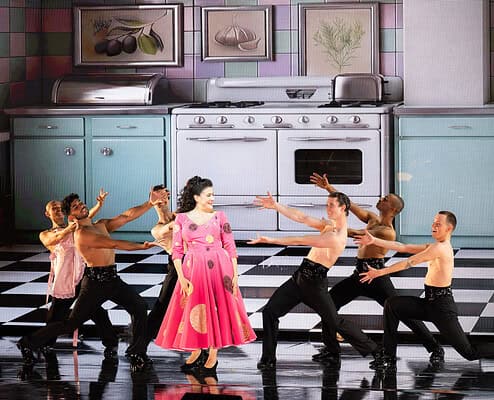 Il Salone Musical - Danza teatrale con attrice in cucina Attrice in costume rosa danza con ballerini in cucina, scena teatrale e coreografia artistica.