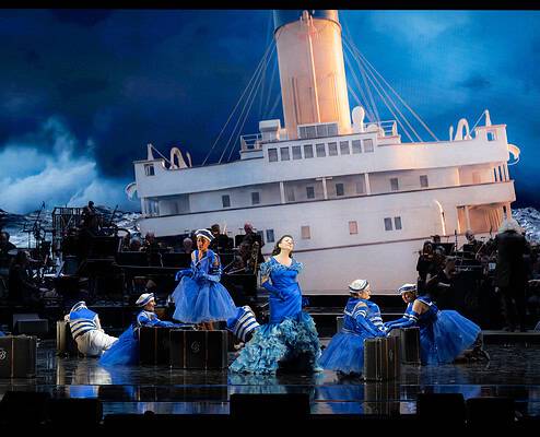Il Salone Musical - Spettacolo teatrale con orchestra Spettacolo teatrale con nave e ballerini in costume blu sul palco.