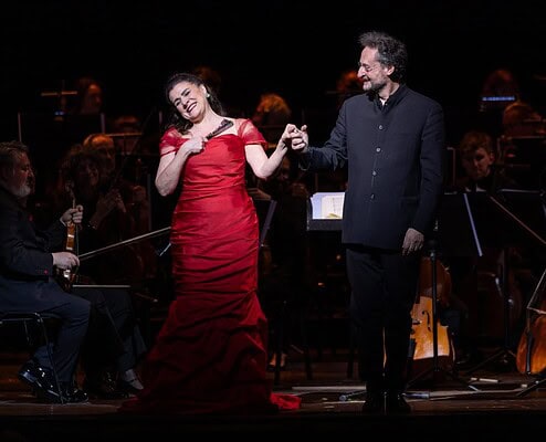 Un duo di artisti sul palco durante un concerto di musica classica con orchestra.