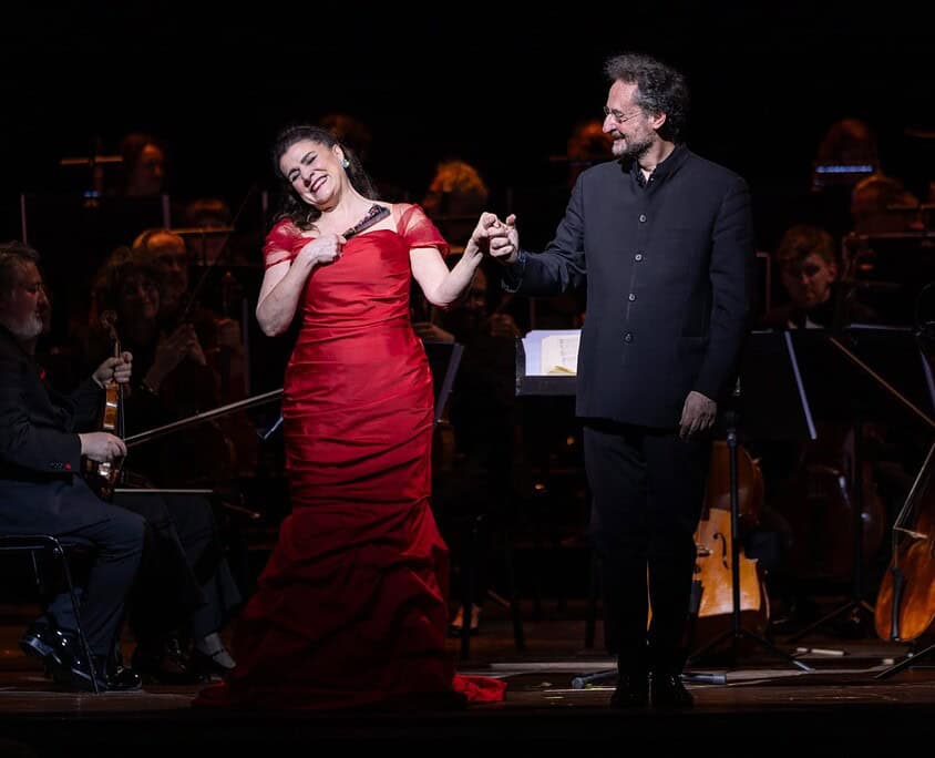 Un duo di artisti sul palco durante un concerto di musica classica con orchestra.