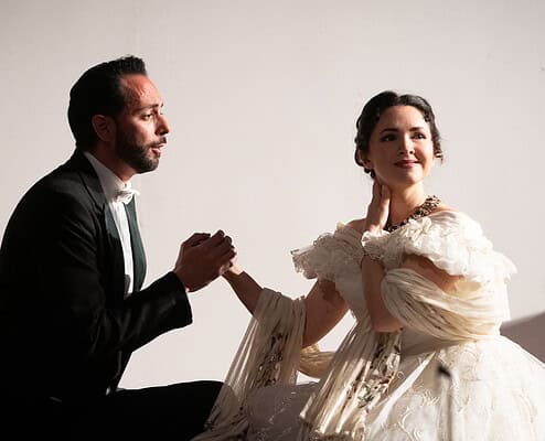 Ragazza in abito da sposa e uomo in abito elegante si tengono per mano in un ambiente elegante.