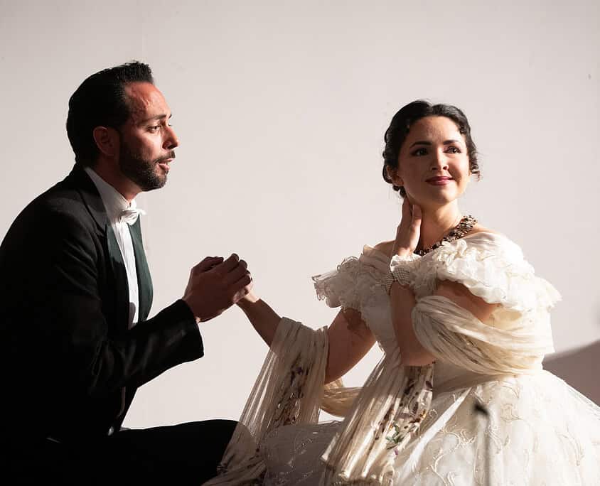 Ragazza in abito da sposa e uomo in abito elegante si tengono per mano in un ambiente elegante.