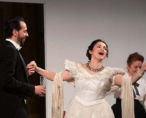 Lettore di musica dal vivo con performer in abiti storici durante uno spettacolo teatrale.