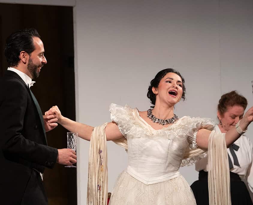 Lettore di musica dal vivo con performer in abiti storici durante uno spettacolo teatrale.