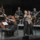 Partitura musicale dal vivo con musicisti e cantanti sul palco di Le Salon Musical.